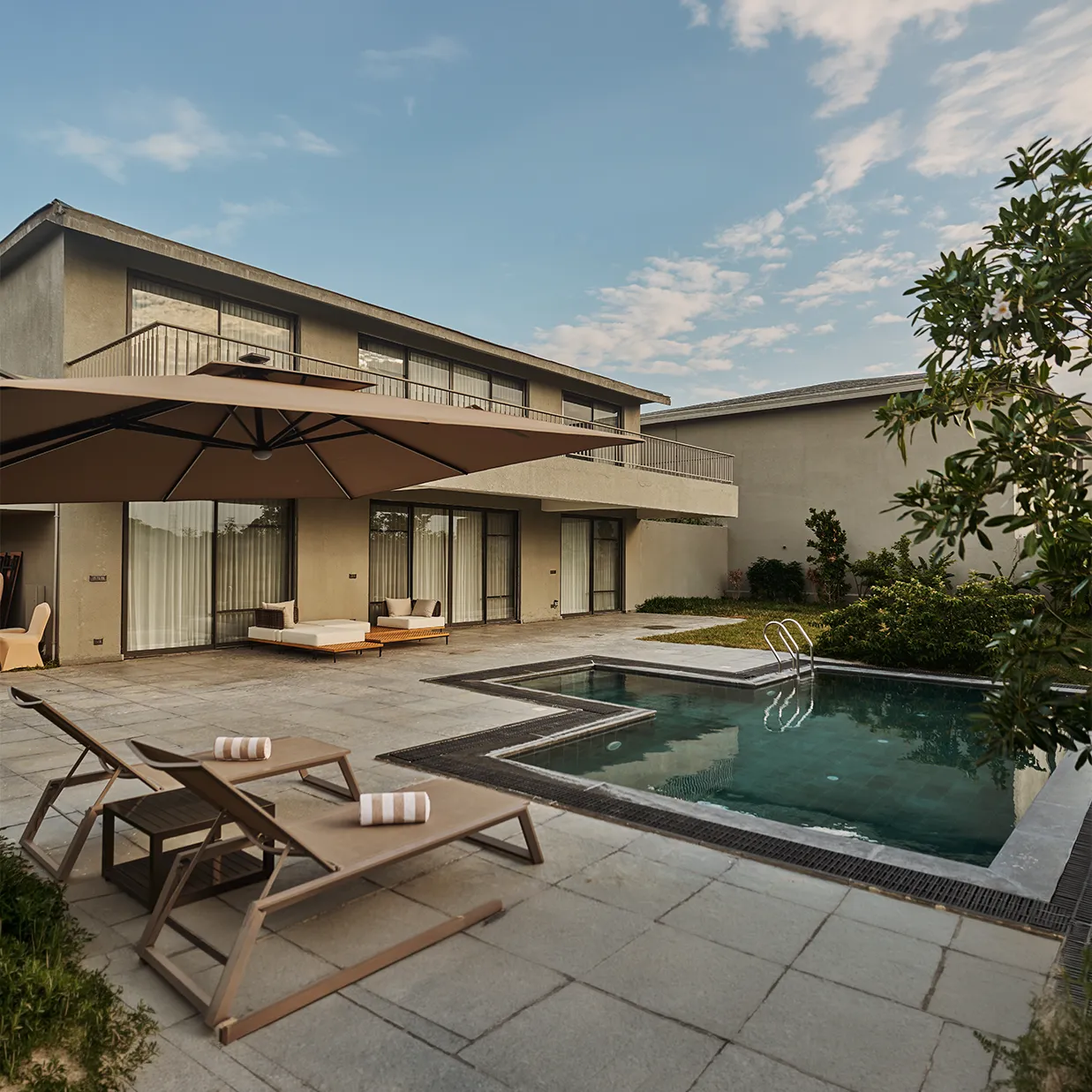 A private pool and stone terrace beside a villa, under an open sky